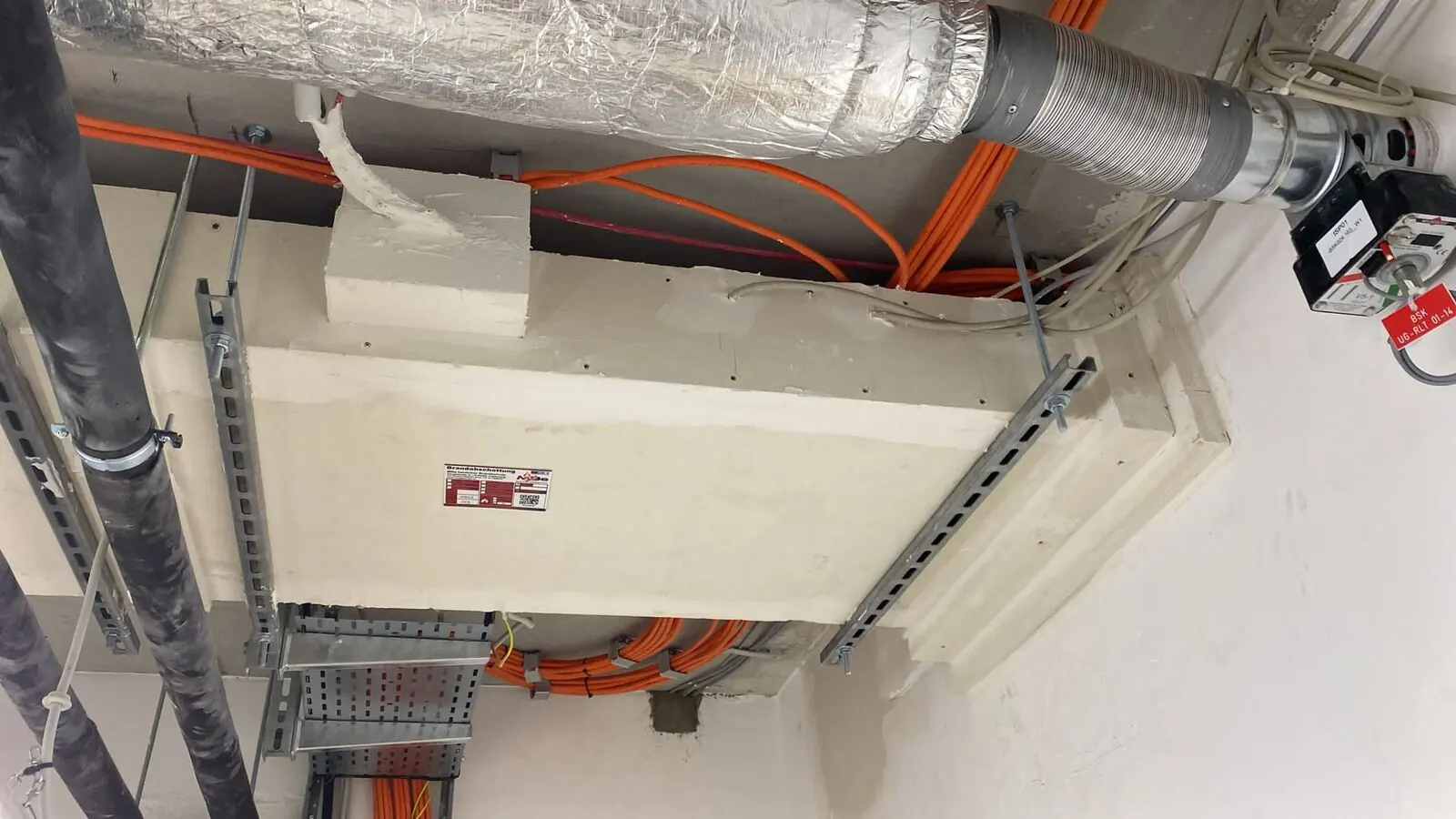 Brandschutzbekleidung einer Lüftungsleitung unter der Decke, daneben Elektrotrassen